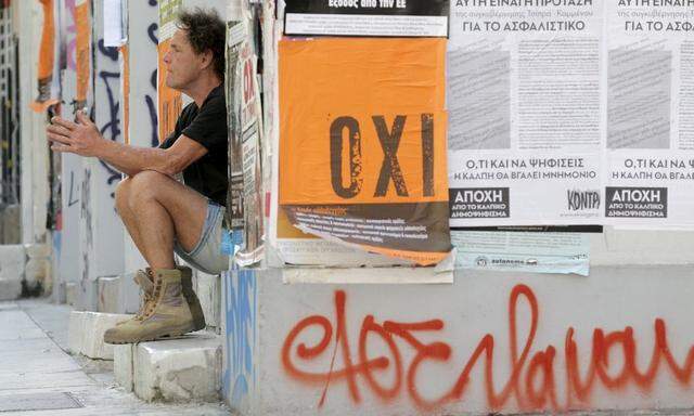 A man sits on a building entrance, next to a referendum campaign poster with the word 'No' in Greek in Athens
