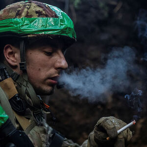 Ukrainian service member smokes in a trench at a position near the frontline town of Bakhmut