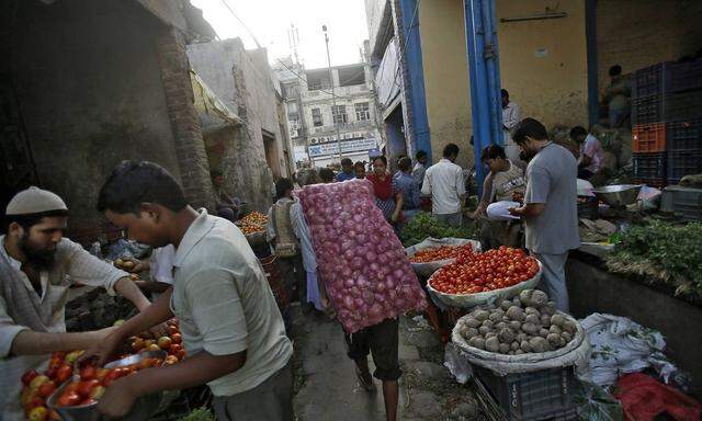 A labourer carries a sack of onions at a wholesale vegetable market in the old quarters of Delhi