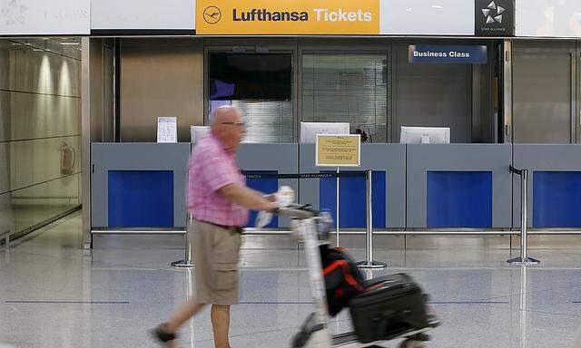 A man pushes his trolley past Lufthansa desk at Athens airport