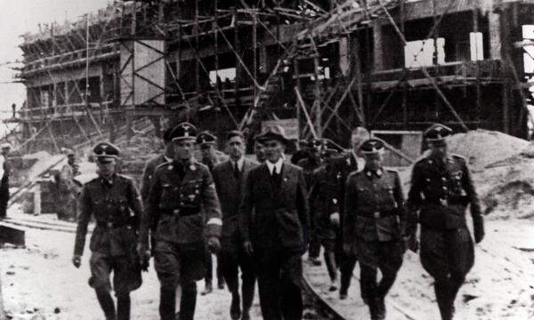 Besichtigung bei Heinrich Himmlers Besuch der Monowitz-Buna-Anlage in Auschwitz. Von links nach rechts: Rudolph Brandt, Heinrich Himmler. Mitte: Max Faust Chefingenieur. Rechts: Rudolf Höß. Datum: 17. Juli 1942 
